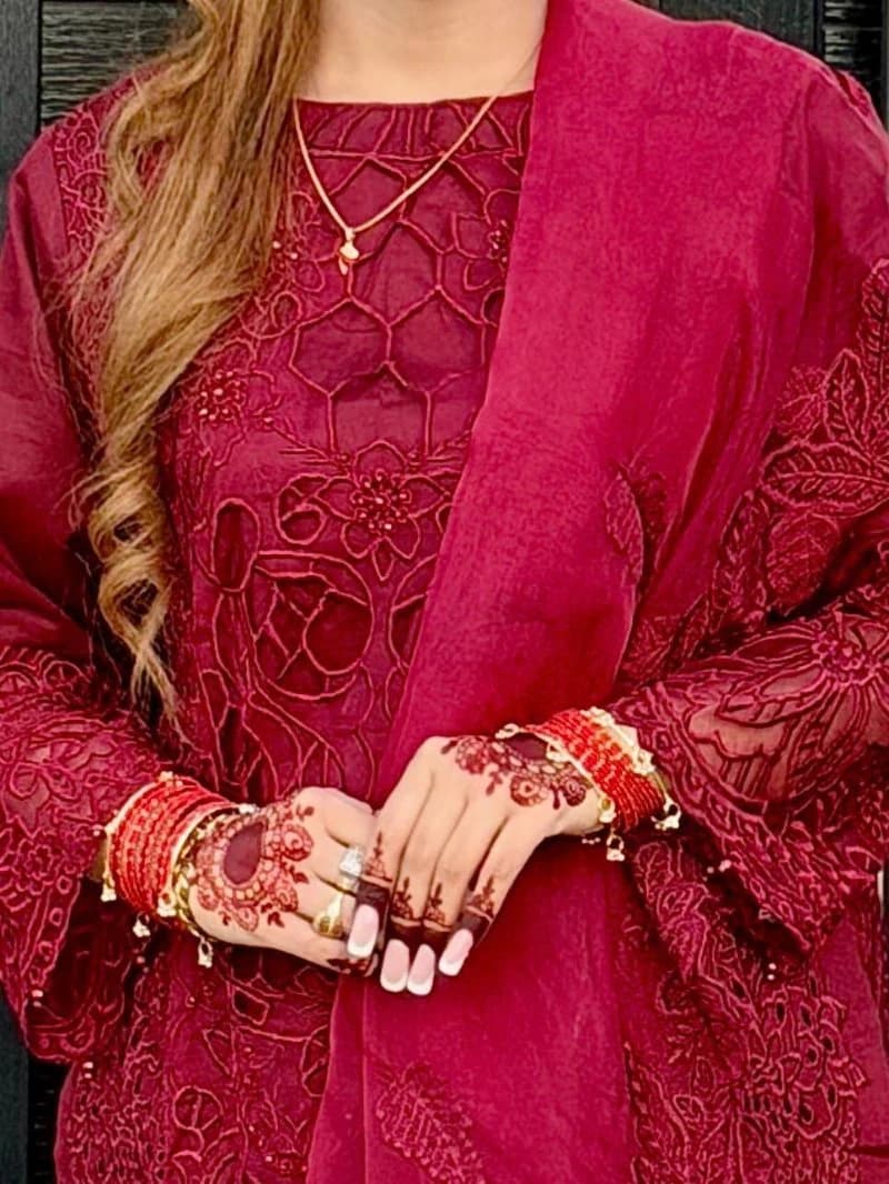 Bridal henna and blush nails against a deep red embroidered outfit and bangles