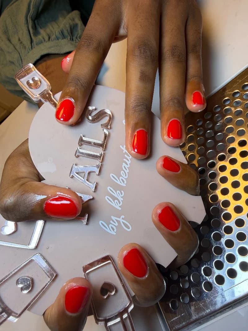 Bright coral-red gel on short rounded nails