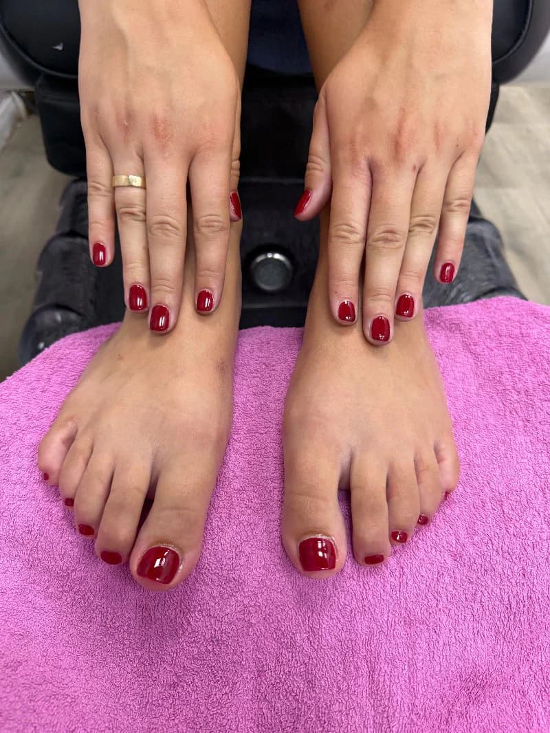 Matching deep red manicure and pedicure on a pink towel