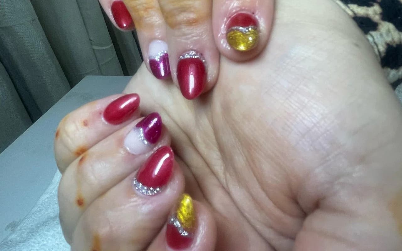 Festive red and magenta gel nails with gold foil and silver glitter accents