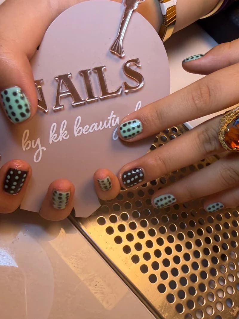 Mint and black polka-dot nail art on short nails