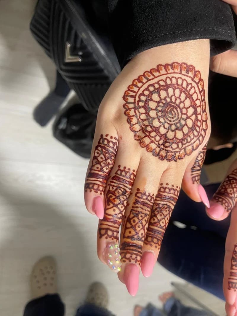 A palm henna mandala with banded finger detail, paired with pink almond nails