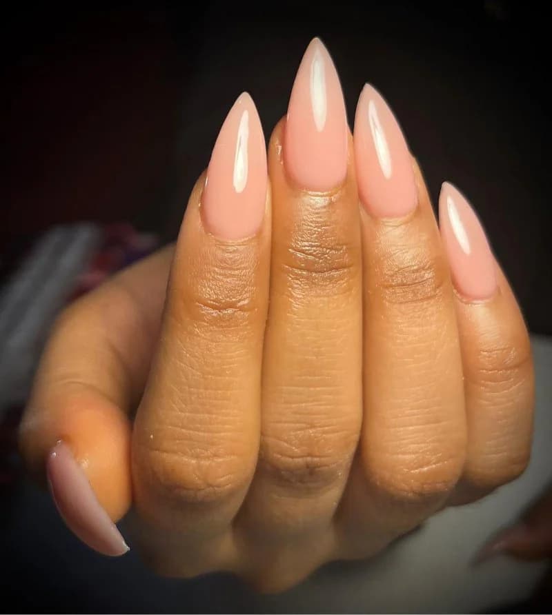 Long peach stiletto nails with a high-gloss finish