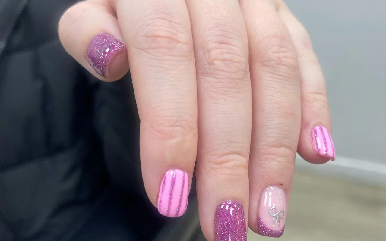 Short square gel nails in candy pink with glitter stripes and a sparkling accent nail