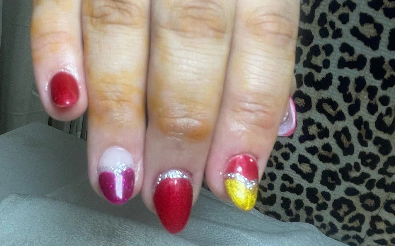 Bold red, magenta and gold almond gel nails with silver glitter half-moons