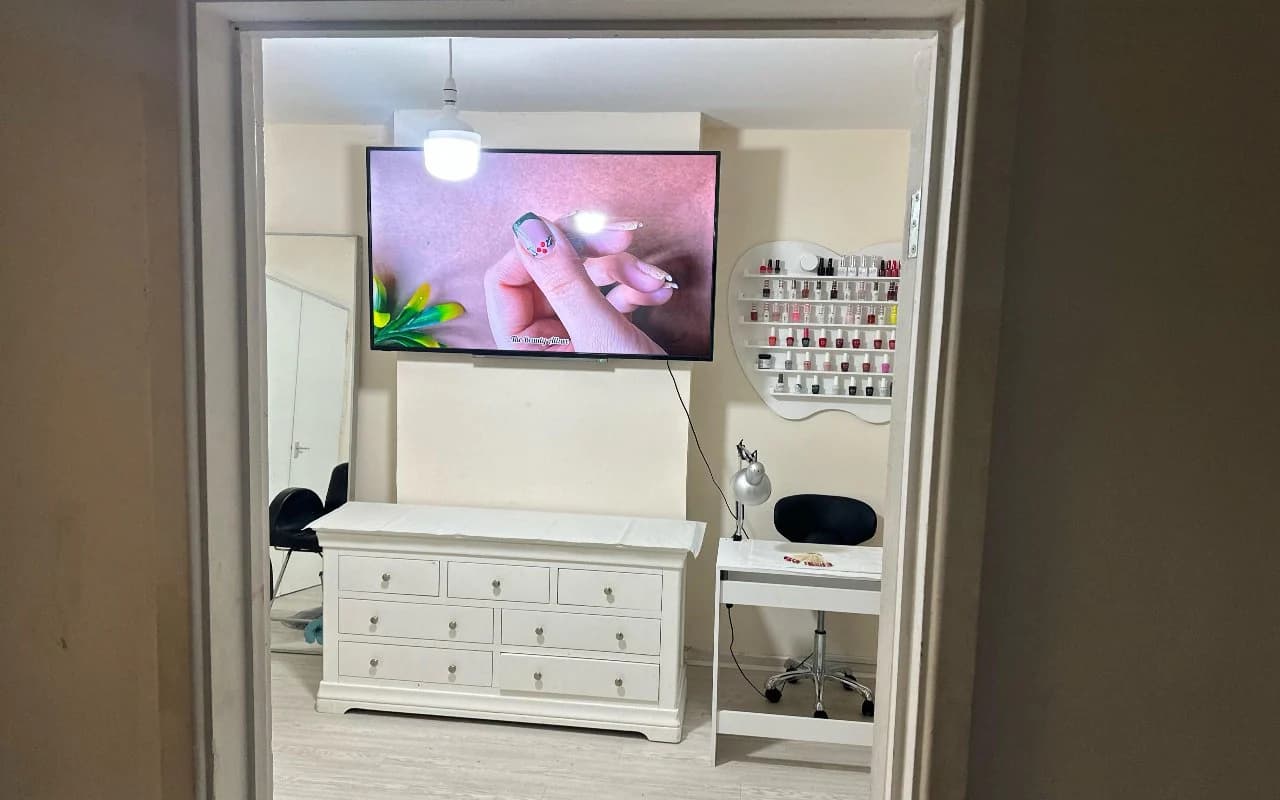The nail station seen through the studio doorway, with a wall-mounted screen and the colour display