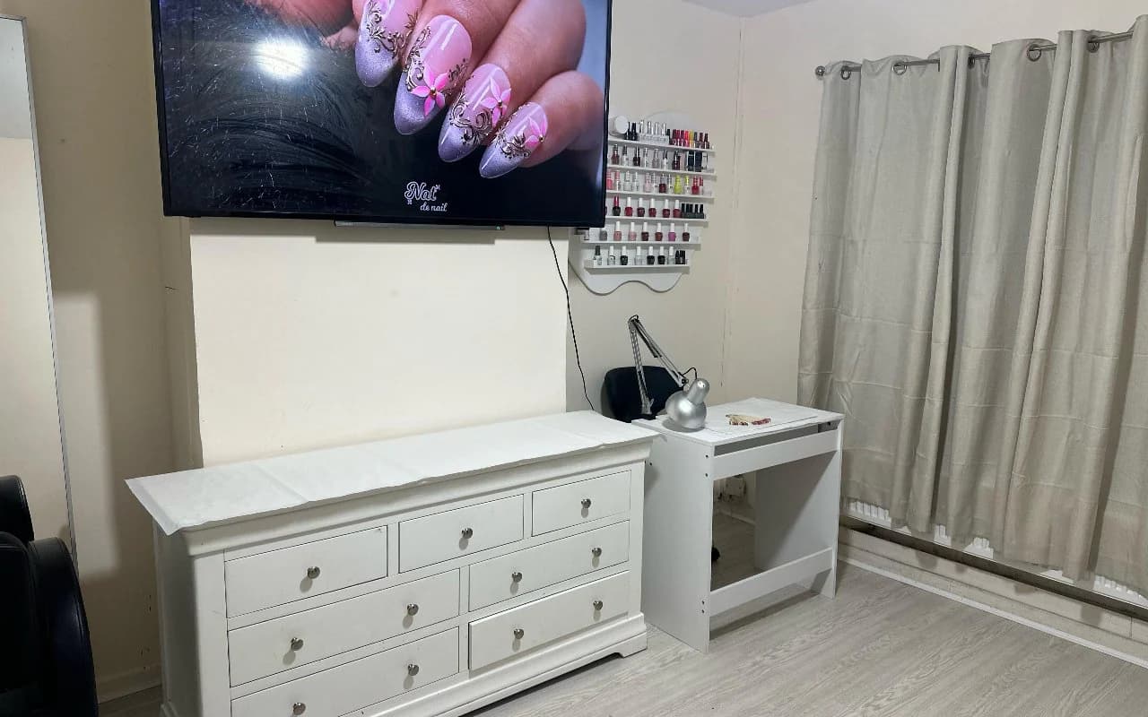 Wide view of the studio showing the nail desk, polish display and soft curtained window