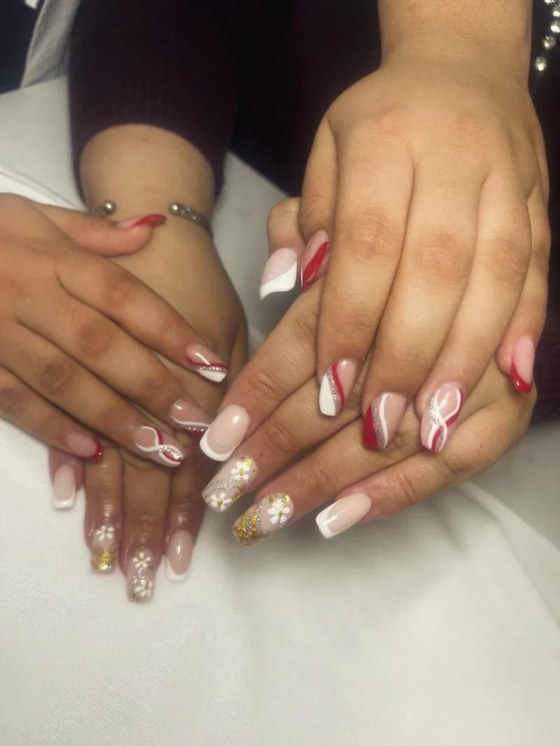 Nude nails with white and burgundy swirl French tips and tiny gold flower details