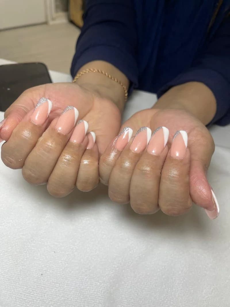 Nude almond nails with crisp white French tips and a glitter accent line